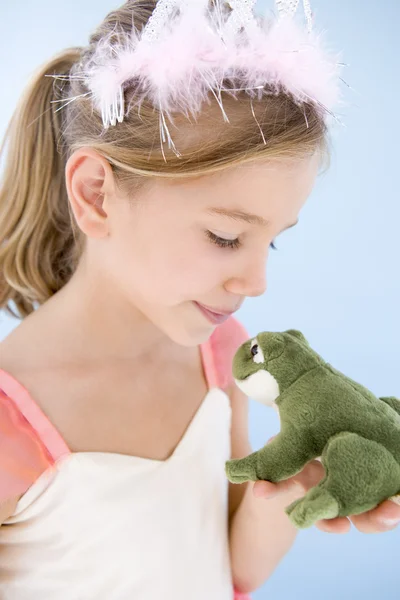 Menina jovem em fantasia de princesa beijando sapo de pelúcia — Fotografia de Stock