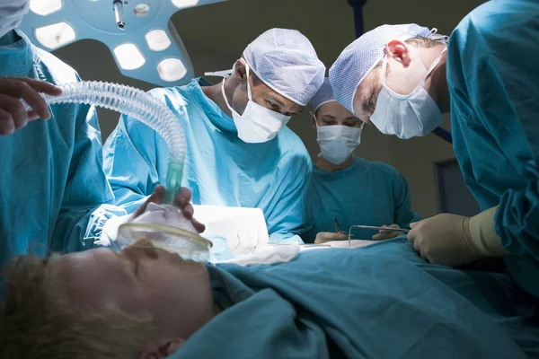 Tres cirujanos operando a un paciente — Foto de Stock
