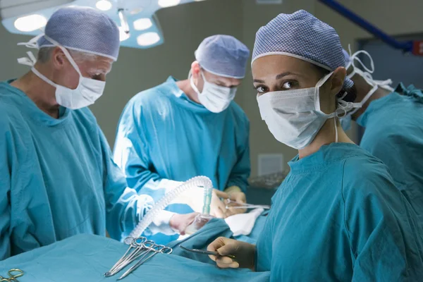 Quatro cirurgiões se preparando para operar em um paciente — Fotografia de Stock