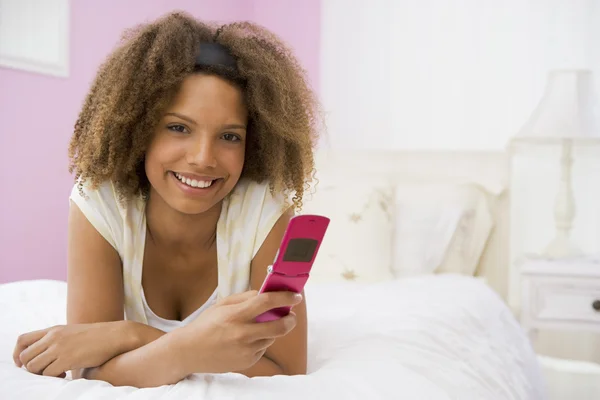 Dospívající dívka leží na posteli pomocí mobilního telefonu — Stock fotografie