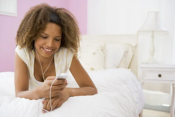 Teenage Girl Lying On Bed Using Mp3 Player — Stock Photo, Image