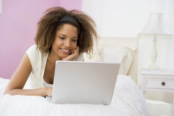 Adolescente menina deitada na cama usando laptop — Fotografia de Stock