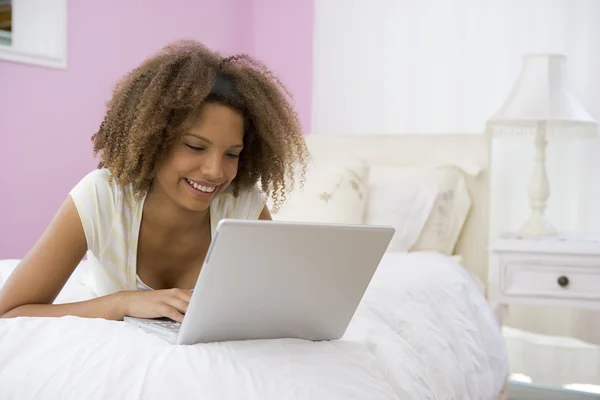 十几岁的女孩躺在床上使用笔记本电脑 — 图库照片