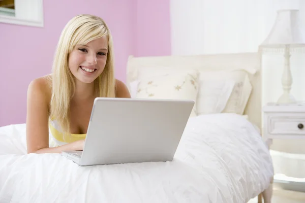 Tienermeisje liggend op bed met behulp van laptop — Stockfoto