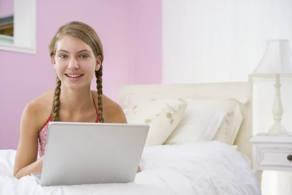 Dizüstü bilgisayar kullanan yatakta yatarken genç kız — Stok fotoğraf