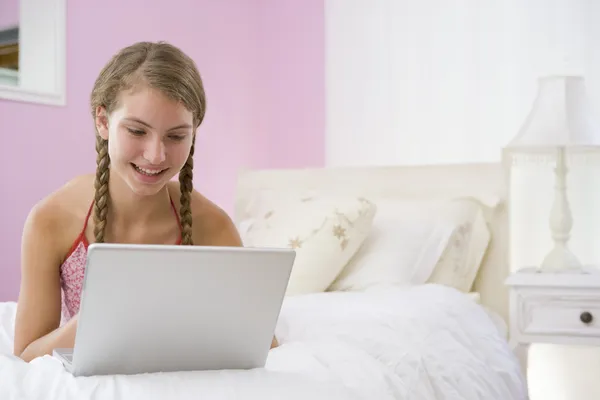 Dospívající dívka leží na posteli pomocí přenosného počítače — Stock fotografie