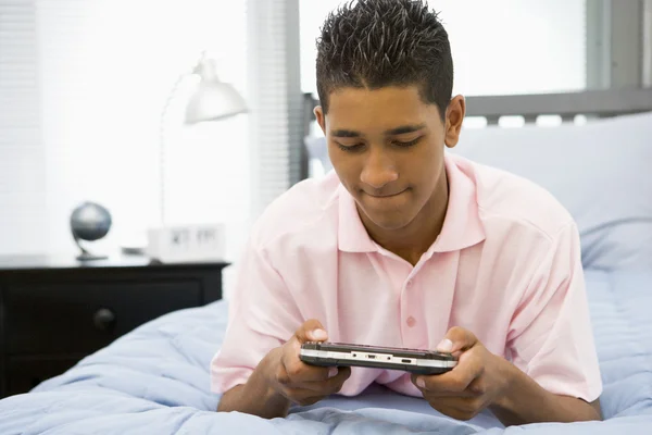 ビデオ ゲームをプレイしてベッドに横になっている 代の少年 — ストック写真