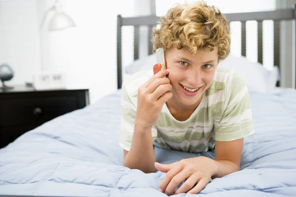 Nastoletni Chłopak Leżał Łóżku Przy Użyciu Telefonu Komórkowego — Zdjęcie stockowe