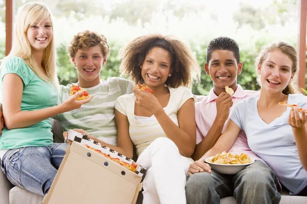 Skupina teenagerů sedí na gauči, jíst pizzu — Stock fotografie
