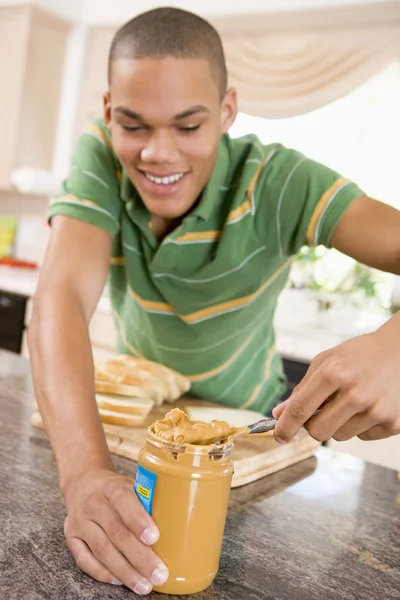 Adolescente macho haciendo sándwich de mantequilla de maní — Foto de Stock