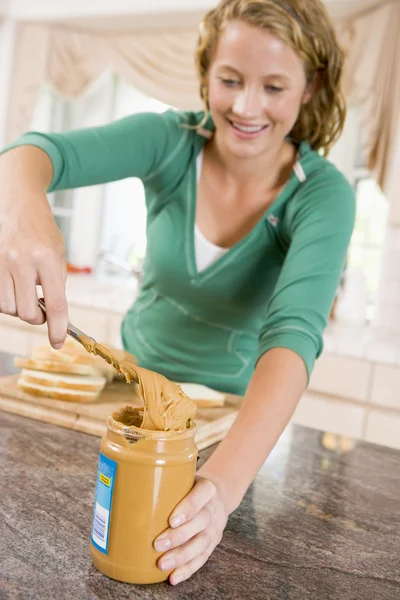 Tienermeisje boterham met pindakaas maken — Stockfoto