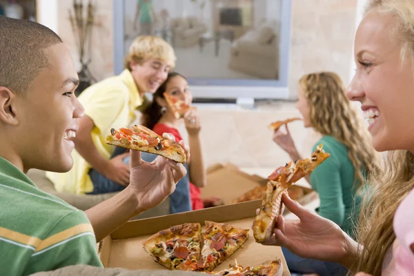 Подростки тусуются перед телевизором, поедая пиццу — стоковое фото