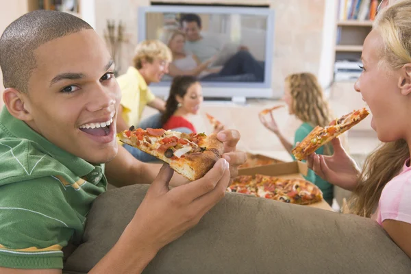 Подростки тусуются перед телевизором, поедая пиццу — стоковое фото
