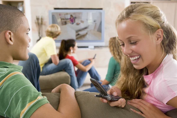 Nastolatki Wychodzić Przed Ekranie Telewizora Przy Użyciu Telefonów Komórkowych — Zdjęcie stockowe