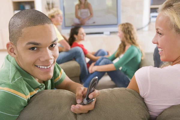 Nastolatki wychodzić przed ekranie telewizora przy użyciu telefonów komórkowych — Zdjęcie stockowe