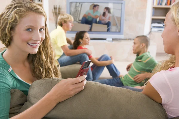 Nastolatki Wychodzić Przed Ekranie Telewizora Przy Użyciu Telefonów Komórkowych — Zdjęcie stockowe