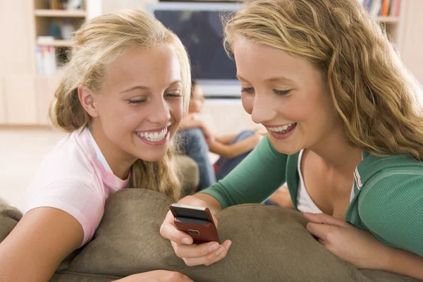 Adolescentes pasando el rato frente a la televisión usando teléfonos móviles — Foto de Stock