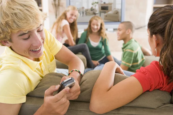 Adolescentes saindo na frente da televisão usando telefones celulares — Fotografia de Stock