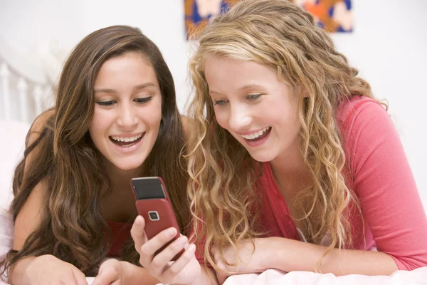 Tonårsflickor liggande på sängen med mobiltelefon — Stockfoto