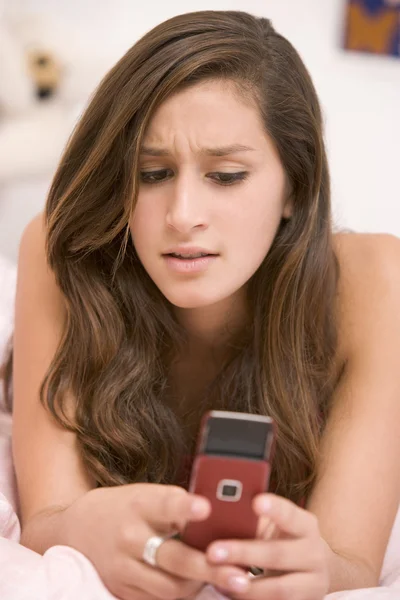 Tienermeisje liggend op haar bed met behulp van mobiele telefoon — Stockfoto
