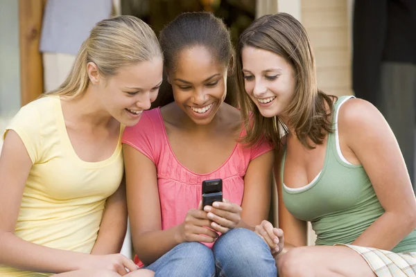 Adolescentes sentadas afuera jugando con el teléfono móvil —  Fotos de Stock