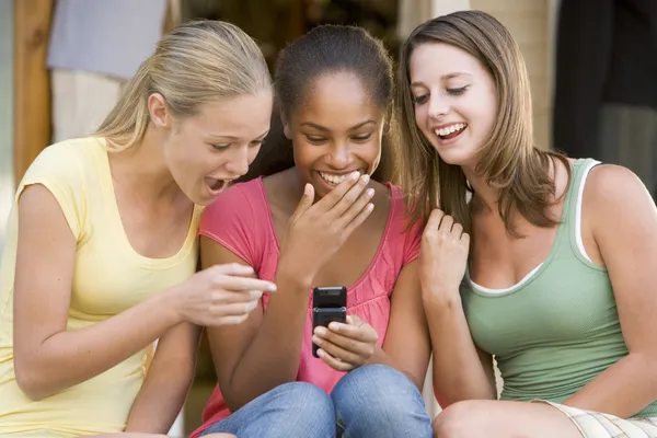 Tiener meisjes zitten buiten spelen met mobiele telefoon — Stockfoto