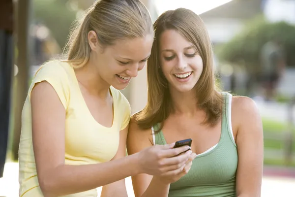 Adolescentes sentadas afuera jugando con el teléfono móvil —  Fotos de Stock