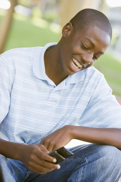 Adolescente menino sentado ao ar livre usando telefone móvel — Fotografia de Stock