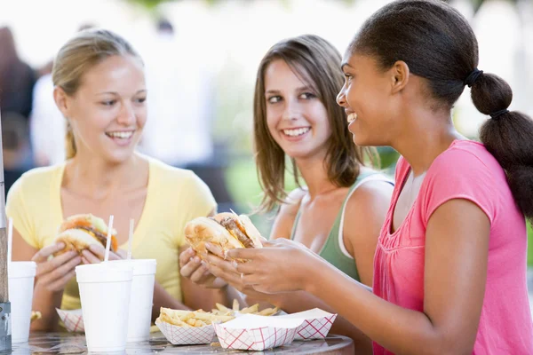Tiener meisjes zitten buiten eten snel voedsel — Stockfoto