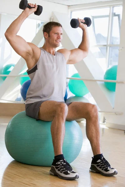 Άνθρωπος χρησιμοποιώντας χέρι βάρη σε ελβετική μπάλα στο γυμναστήριο — Φωτογραφία Αρχείου