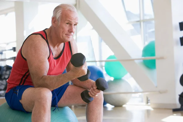 Spor salonunda swiss Ball el ağırlıkları kullanarak adam — Stok fotoğraf