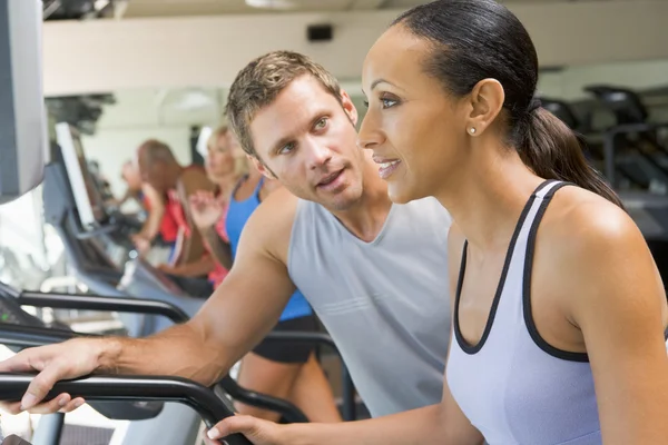 私人教练鼓励使用在健身房的跑步机的女人 — 图库照片