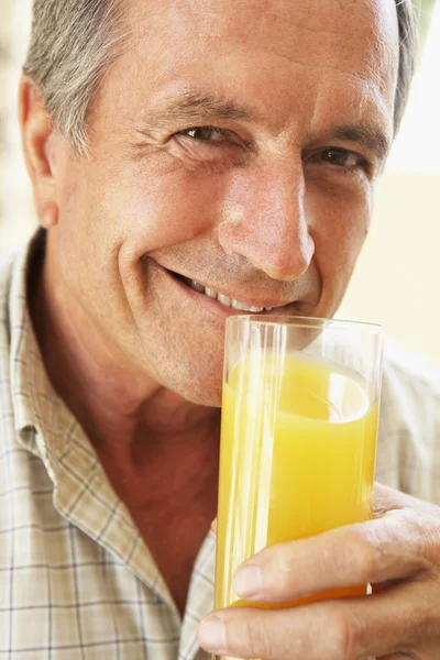 シニアの人カメラに笑顔とオレンジ ジュースを飲む — ストック写真