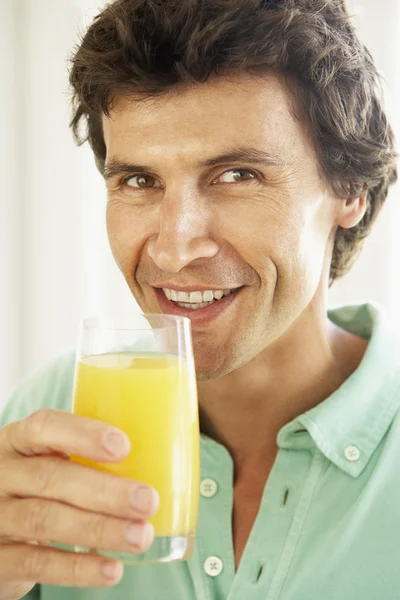 Homem adulto médio bebendo um copo de suco de laranja — Fotografia de Stock