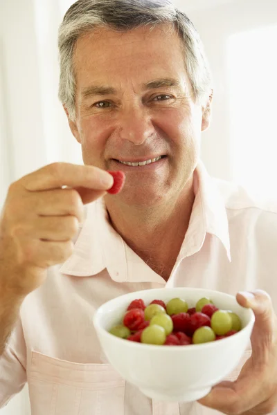 Mellersta åldern man äter färsk frukt — Stockfoto