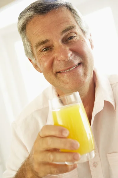 Homem de meia idade bebendo um copo de suco de laranja — Fotografia de Stock