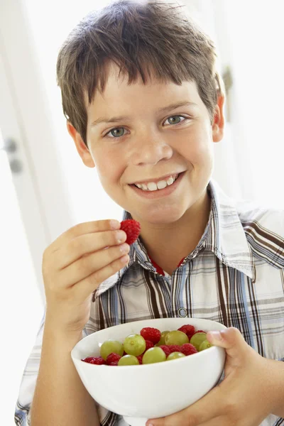 Mladý chlapec jíst mísa s čerstvým ovocem — Stock fotografie