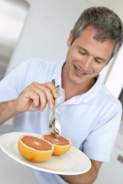中间岁的男子吃新鲜葡萄柚 — 图库照片