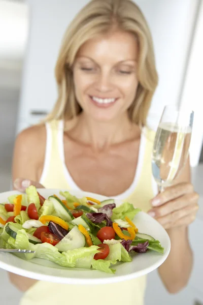 Mujer adulta sosteniendo una copa de vino y ensalada fresca —  Fotos de Stock