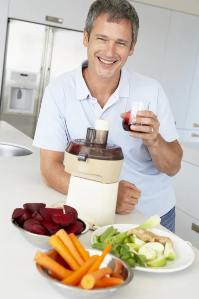 Hombre de mediana edad haciendo jugo de verduras frescas — Foto de Stock