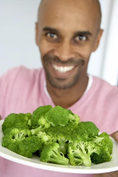 Hombre de mediana edad sosteniendo una placa de brócoli — Foto de Stock