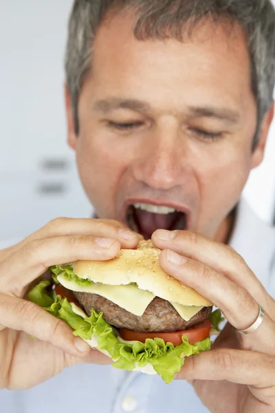 ハンバーガーを食べて中年の男 — ストック写真