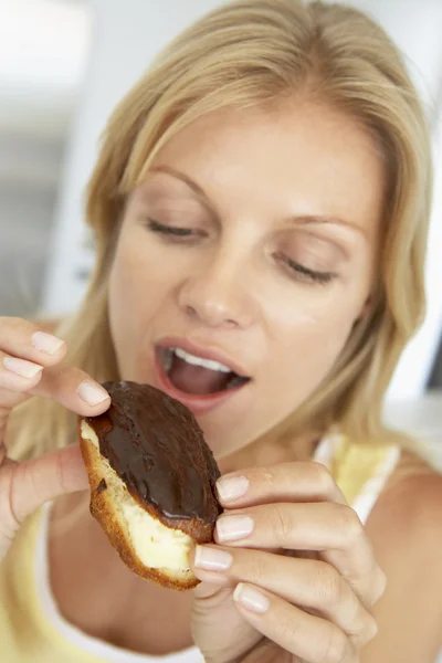 Mid Adult Woman Comendo um Eclair Chocolate — Fotografia de Stock