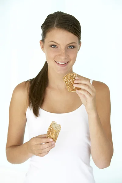 Mujer joven comiendo un rollo de pan marrón —  Fotos de Stock
