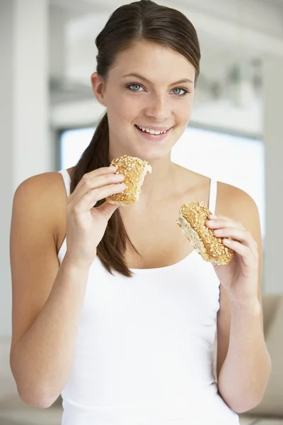 年轻女子吃褐色面包卷 — 图库照片
