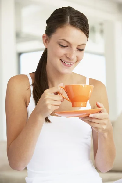 Молодая женщина пьет из оранжевой чашки — стоковое фото