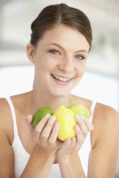 Молодая женщина держит свежие фрукты и улыбается перед камерой — стоковое фото