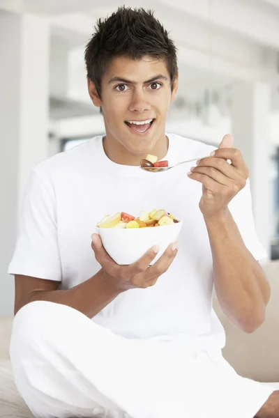 Junger Mann isst frischen Obstsalat — Stockfoto