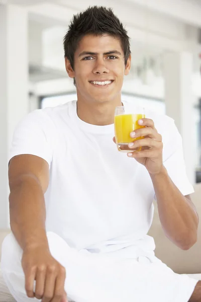 Mladý muž pije pomerančový džus — Stock fotografie