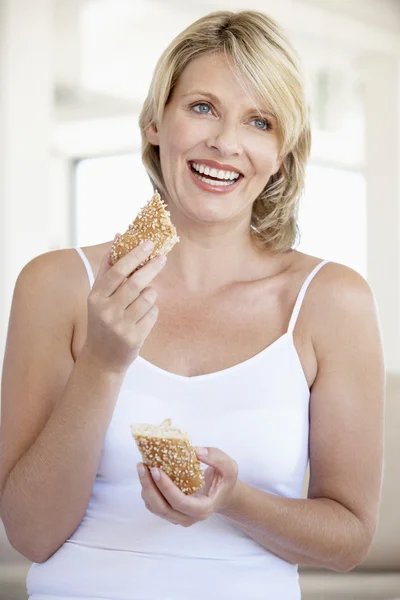 成人女性の新鮮な茶色のパンを食べて半ばロールします — ストック写真